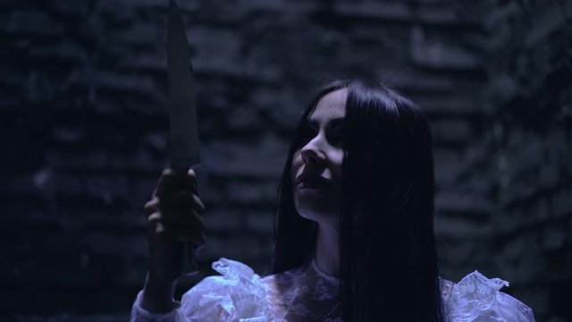 Female psycho maniac preparing to stab victim, holding sharp knife in hand
