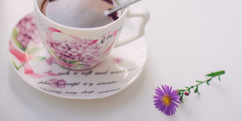 Black tea in an elegant vintage porcelain cup on the white table.