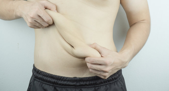 Close up man holding excessive fat belly on white background. Diet, weight loss, slim body, healthy lifestyle concept.