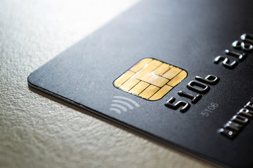 Black credit card with chip and contactless pay technology close-up. Low key shot with old credit card. - obrazy, fototapety, plakaty