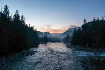 Scenic view of river passing through mountains during sunset