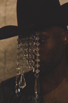 Close up of model wearing hat with strands of crystal