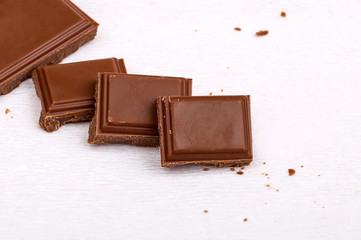Milk chocolate pieces on a white background. Half a chocolate bar. Dark bitter chocolate. Roughly...