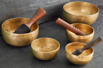 Tibetan singing bowls with sticks on the dark background - old music instruments for meditation, relaxation and healing after yoga practice 