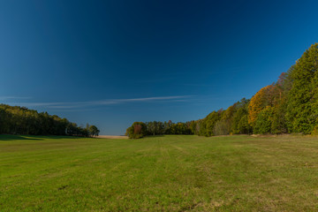 Color autumn meadow and forests with blue sky in Kokorinsko area in Bohemia