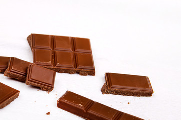 Milk chocolate pieces on a white background. Half a chocolate bar. Dark bitter chocolate. Roughly cut chunks of a chocolate bar.