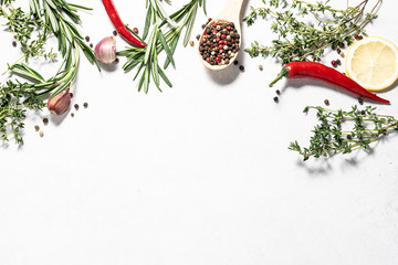 Flat lay overhead of different spices, herbs and vegetables on white marble background with copy...