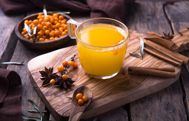 cup of buckthorn  tea with lemon and spices on wooden table