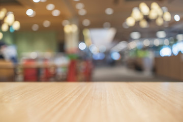 Obraz premium Empty light colored wood table top and blur of food court/restaurant background/selective focus. For montage product display.