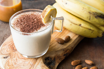 Fresh Made Chocolate Banana Smoothie on a wooden table. Selective focus. Milkshake with nuts. Protein diet. Healthy food and drink concep
