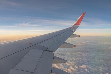 Naklejka na ściany i meble Wing of the plane outside of the window. Airplane above the sky. Airplane above the cloud. Looking outside the airplane window.