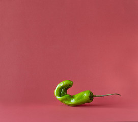 Trendy ugly organic hot pepper on pink background.