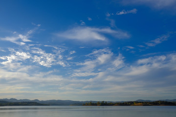 Fototapeta na wymiar Blue sky with some white clouds over a lake
