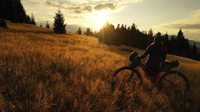 4k drone clip with two mountain bikes and a tent on a mountain meadow at sunrise in autumn season. Adventure cycling concept.
