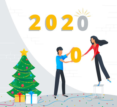 Small business people are preparing for the New Year party in the office, corporate team building the new year gold numbers 2020 for new year celebration near the christmas tree with gift boxes.