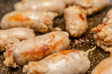 Sausages fried in a frying pan close up