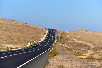 Cars on the asphalt road among lava poles on Lanzarote, Canary Islands, Spain
