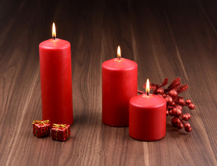 Red christmas candles stock images. Red christmas candles on a wooden background. Christmas still life concept. Three red candles with gifts. Red christmas decoration images