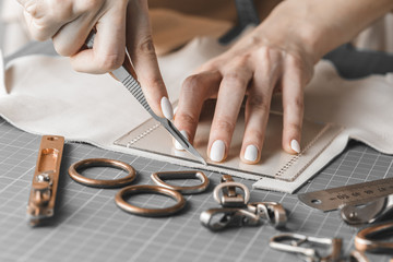 Woman measuring and cutting leather in a workshop