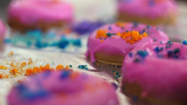 Doughnut shaped soaps being decorated with pink soap and colored bath salts for home made organic aromatherapy soap