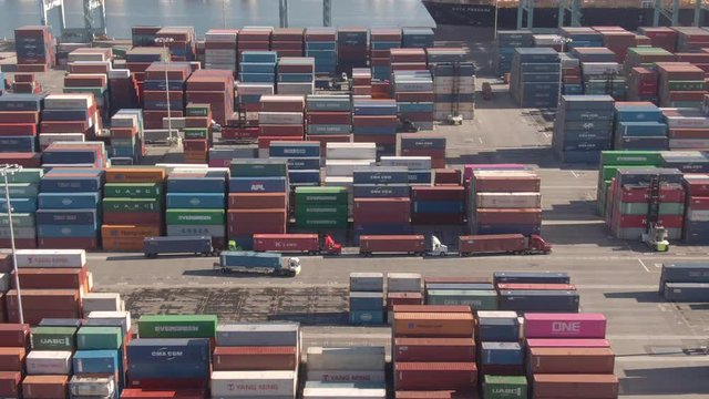 PORT OF LOS ANGELES, CALIFORNIA, UNITED STATES OF AMERICA, MARCH 2019: DRONE: Flying along a cargo truck hauling a container across the busy Port of Los Angeles. Truck navigates the industrial harbor.