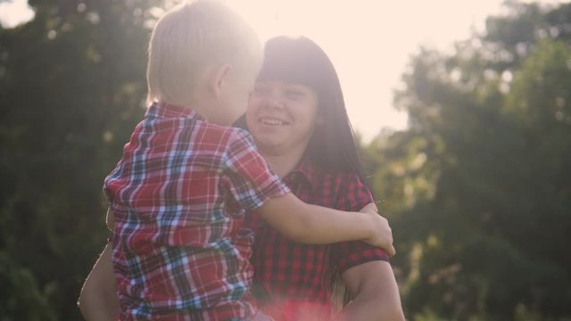 happy family mother's day funny the nature slow motion video teamwork outdoors. mom girl holds son boy in arms smiling sunlight cute video care. mother and son circling cuddle a friendly family