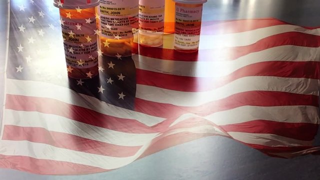 4k Slow Motion Medicine Bottles and Pills Falling With Ghosted American Flag Waving. The medicine bottle labels are non-proprietary with fictitious names, addresses and information designed specifical