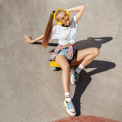 Sexy young woman in sunglasses sitting on skateboard or pennyboard at the skatepark. Freedom...