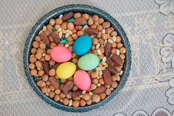 Novruz symbol on xoncha on white background Azerbaijan holiday . There are colored eggs, hazelnuts, dates, and peanuts in the cabin.