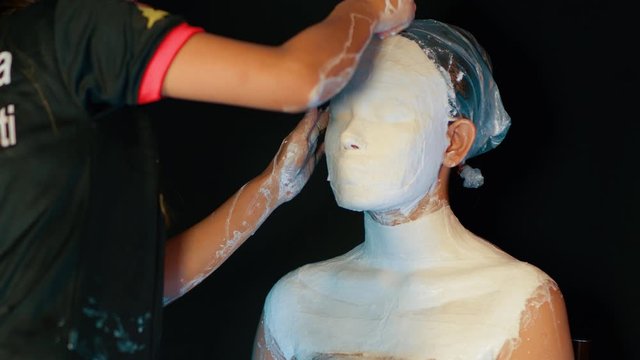 Prosthetic plaster of paris mask cast layers being applied to a waiting model, closeup 