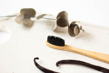 eco friendly toothbrushe and vanilla eucalyptus branch on marble background. Dental and healthcare concept. Top view, flat lay.
