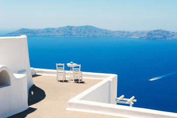 Two chairs on the terrace with sea view. White architecture on Santorini island, Greece. Travel destinations concept - obrazy, fototapety, plakaty
