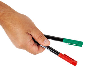 The hand holds two felt-tip pens of red green color on a white background. Isolate, close up.