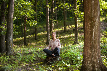 Beautiful woman meditating in the forest on a sunny morning