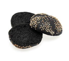 Black round bread dusted with sesame seeds on a white background on a white background