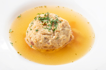 single speckknoedel in soup on wood
