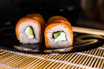 Sushi rolls with salmon and avocado on a dark background