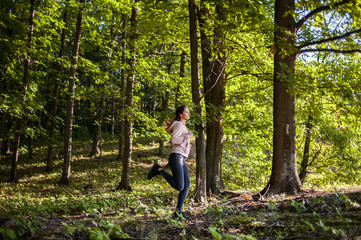 Young girl jogging in the woods on a sunny morning.