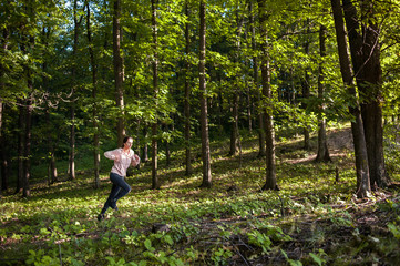 Naklejka na ściany i meble Young girl jogging in the woods on a sunny morning.