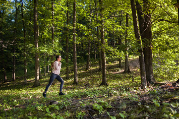 Young girl jogging in the woods on a sunny morning.