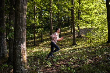 Young girl jogging in the woods on a sunny morning.