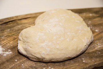 Fototapeta na wymiar dough with flour on a wooden background