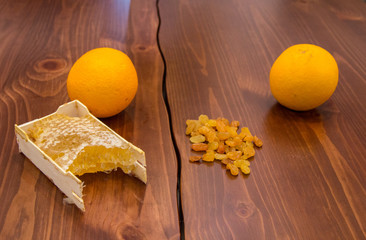 honey in honeycomb next to raisins on a wooden background