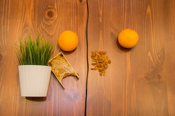 honey in combs next to raisins with green grass leaves on a wooden background