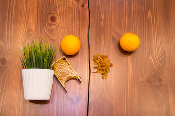 honey in combs next to raisins with green grass leaves on a wooden background