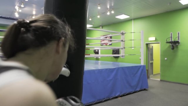 Girl Boxing in Boxing gloves, beats a Boxing bag in the gym