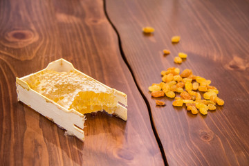 honey in honeycomb next to raisins on a wooden background