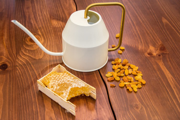 honey in honeycomb next to raisins on a wooden background
