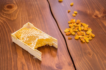 honey in honeycomb next to raisins on a wooden background