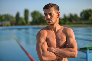 Swimmer standing next to a pool on a sunny morning